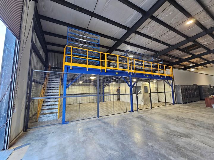 Industrial warehouse mezzanine with blue structure and yellow safety railings