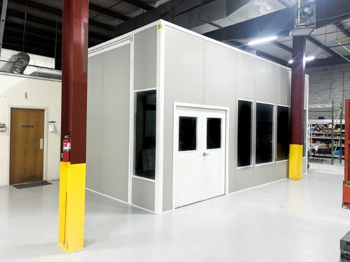 Modular in-plant office with white walls, windows, and door in warehouse setting