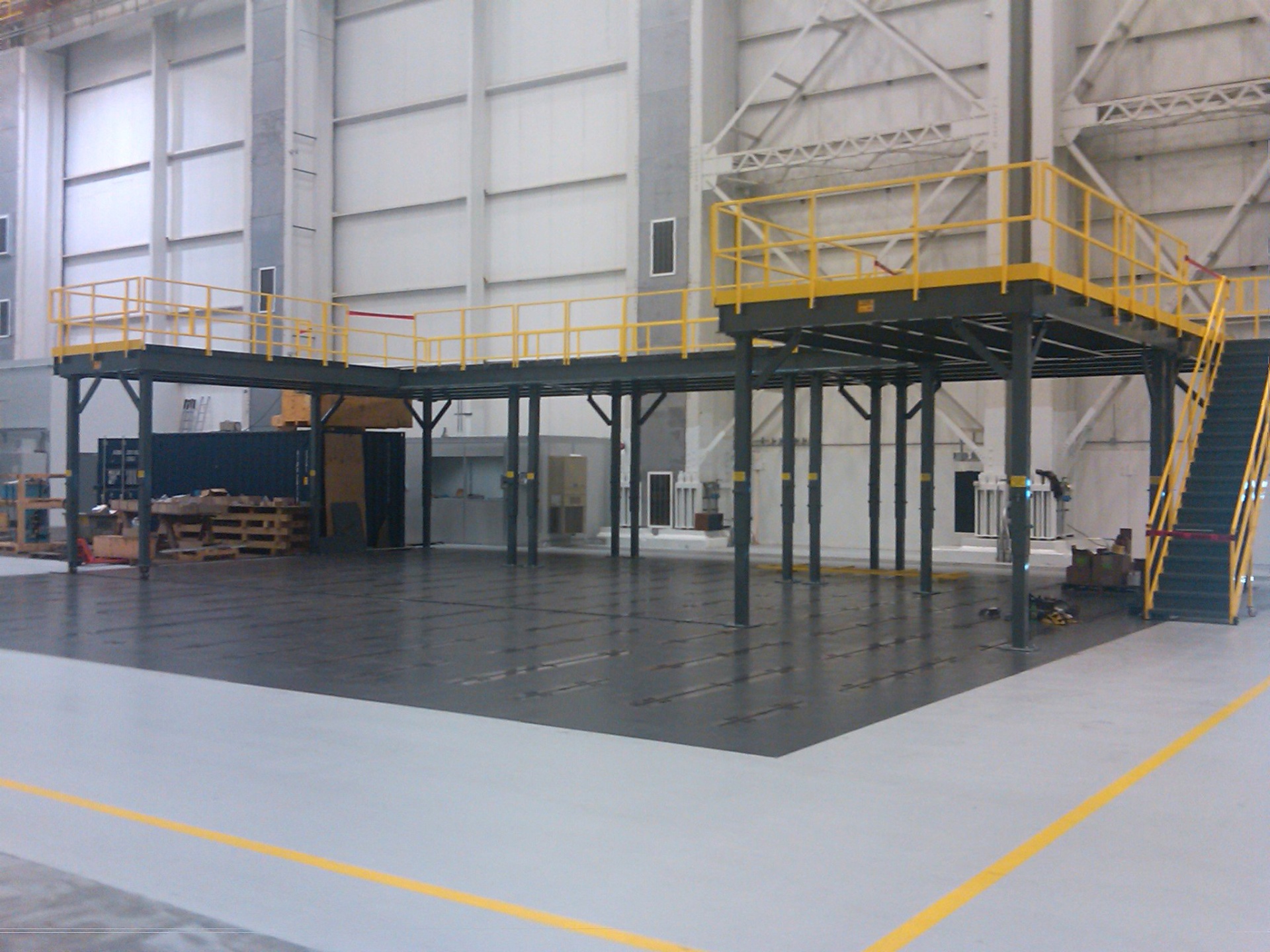 Large industrial mezzanine with yellow safety railings and staircase in warehouse facility