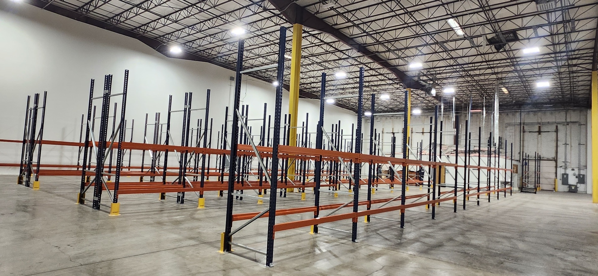 Large pallet racking installation with black uprights and orange beams with column protectors in Columbus OH warehouse