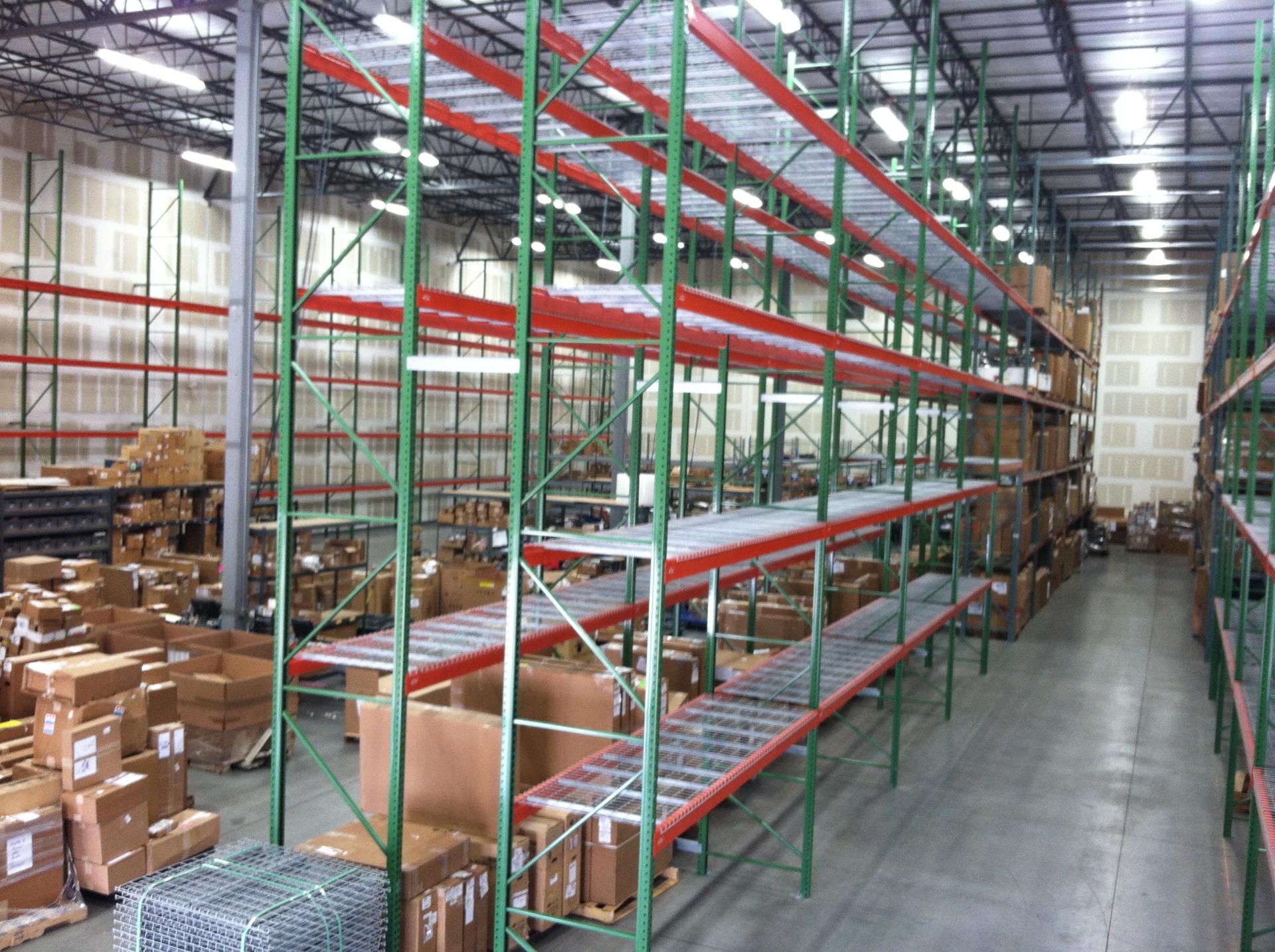 Large-scale pallet racking with green uprights and red beams fully stocked in Hebron KY distribution center