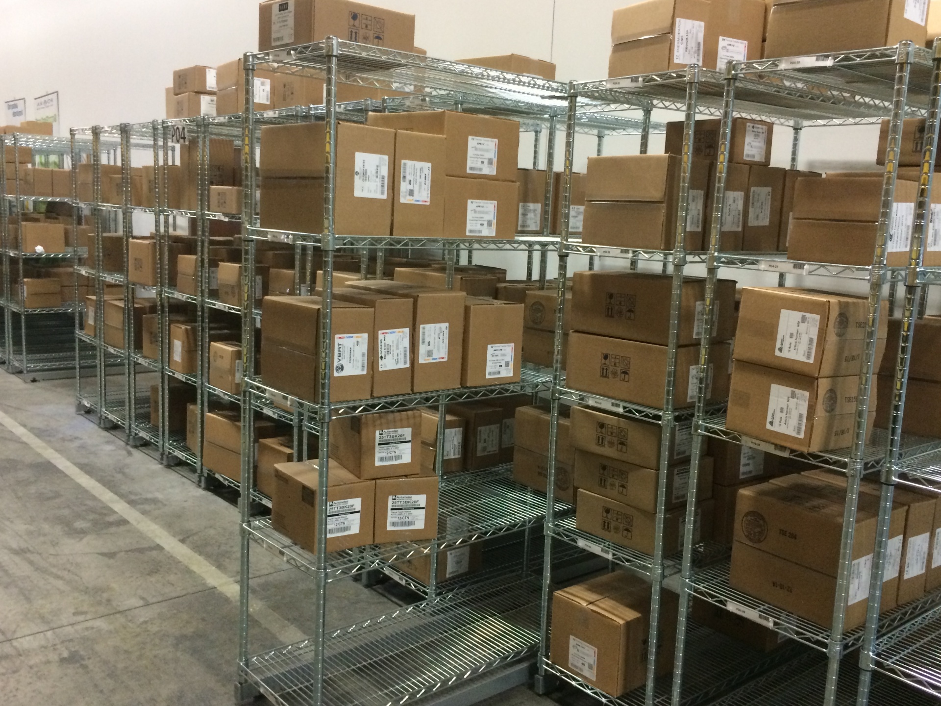 Chrome wire shelving units holding labeled cartons in a parts storage area